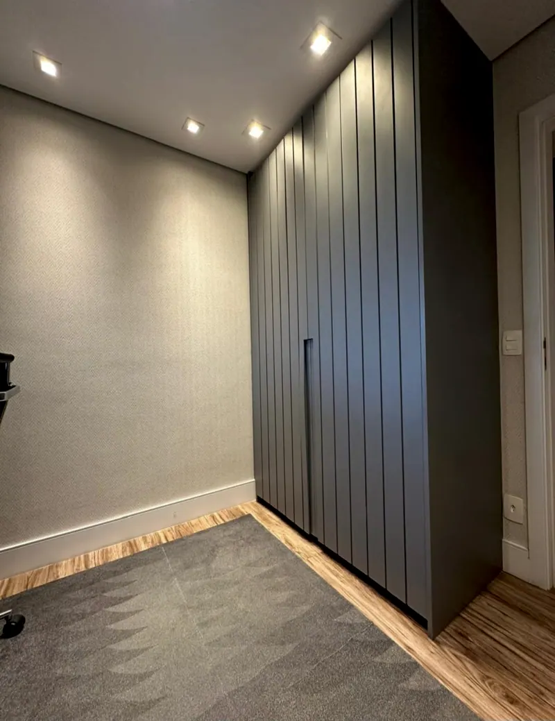 Corredor com armário alto cinza escuro de portas ripadas
