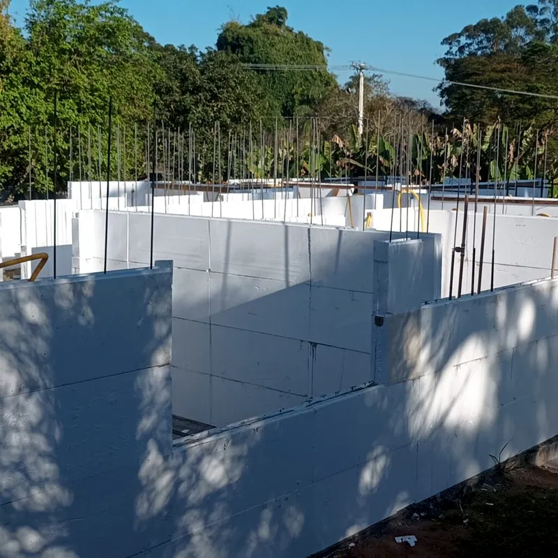 Paredes de blocos de EPS na obra, com árvores ao fundo